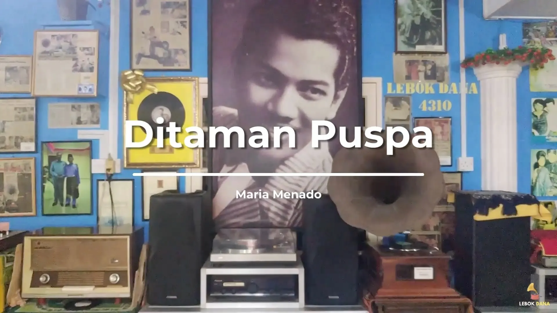 Kad tajuk video Ditaman Puspa nyanyian Maria Menado dari filem Selendang Delima, berlatarkan potret P. Ramlee dan gramofon di Galeri Lebok Dana