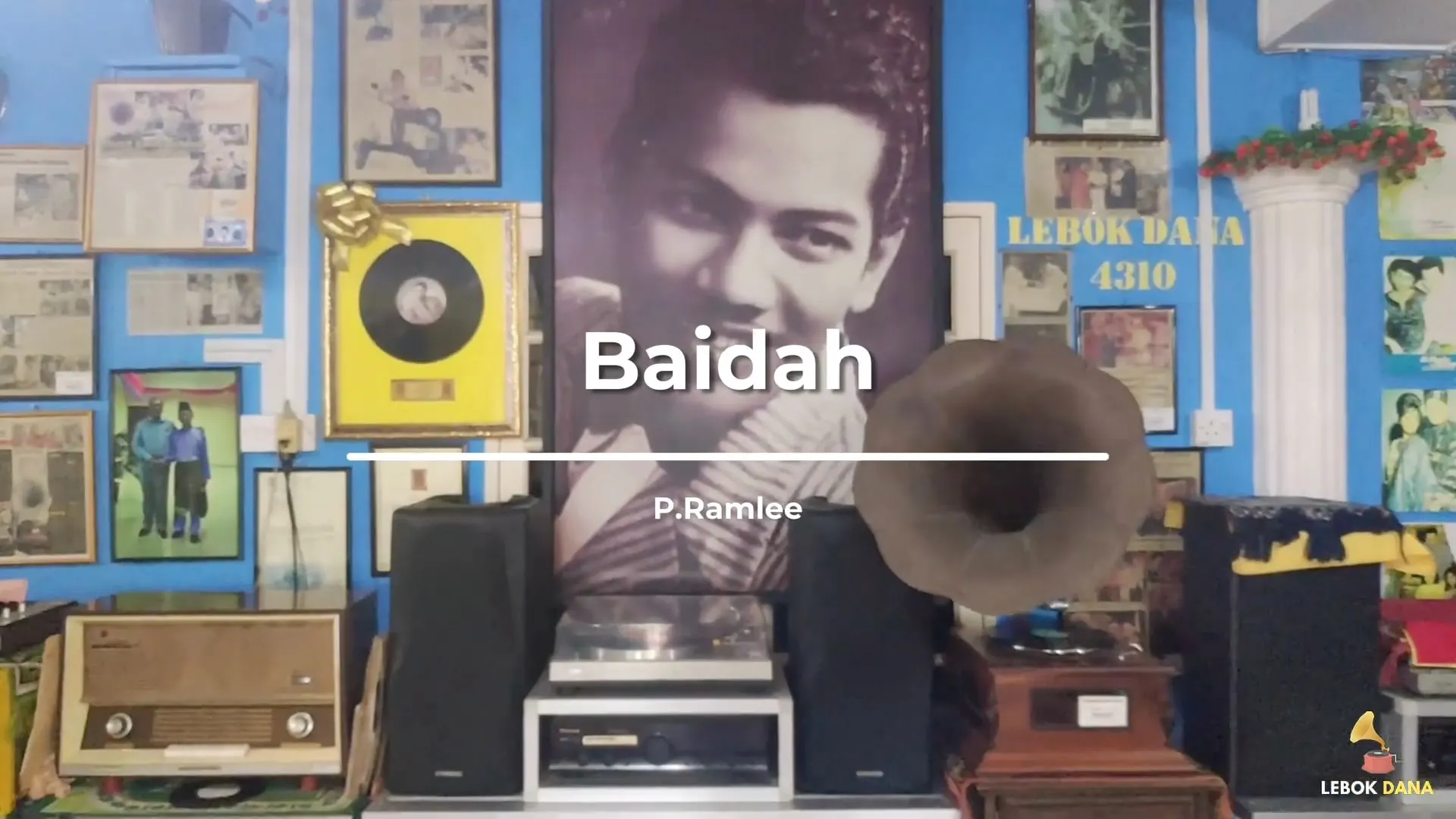 Kad tajuk video Baidah nyanyian P. Ramlee, dengan potret besar P. Ramlee, piring hitam berbingkai dan gramofon di dinding Galeri Lebok Dana